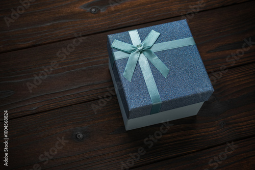 Blue Gift Box with Light Blue Ribbon on Dark Wood Background - Elegant Present for Special Occasions photo