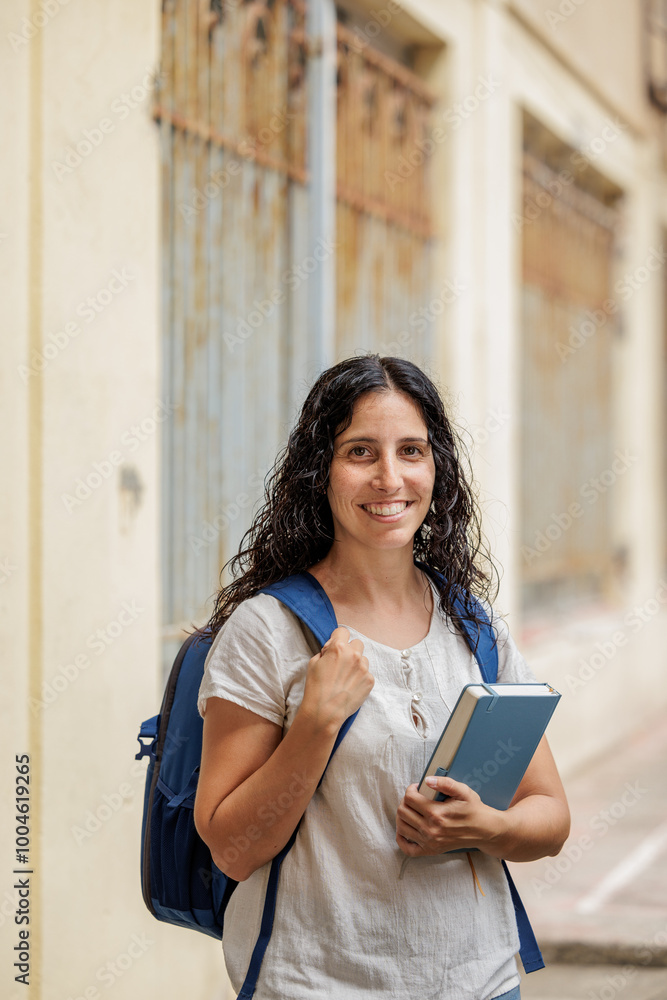 College or university student walks with her backpack and books around the campus. Learning new knowledge. Education is a right for all people. College or university student walks with her backpack and books around the campus. Learning new knowledge. Education is a right for all people.