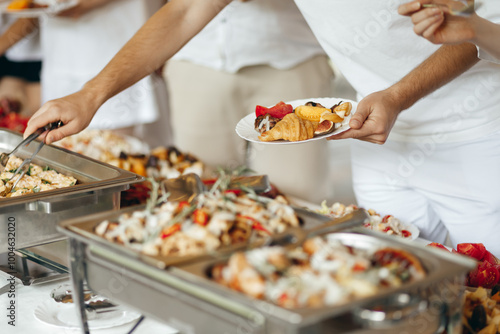 Hands Taking Food from a Table at a Swedish Buffet Party. People enjoying different snacks at a festive gathering