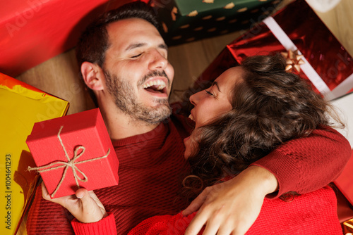 Young couple in love very happy celebrating Christmas day in their new house. The gifts have arrived. Sharing moments with their loved ones. New cozy home to welcome the new year with family. photo