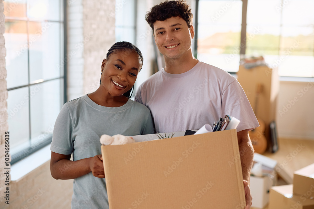 Happy multiracial couple relocating into new house and looking at camera. Happy multiracial couple relocating into new house and looking at camera.
