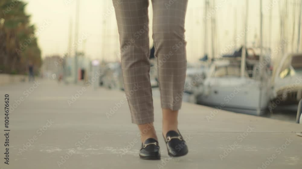 Businesswoman Walk Along Marina, Showcasing Loafers and Dress Pants. Yachts and Boats Create Picturesque Backdrop Businesswoman Walk Along Marina, Showcasing Loafers and Dress Pants. Yachts and Boats Create Picturesque Backdrop