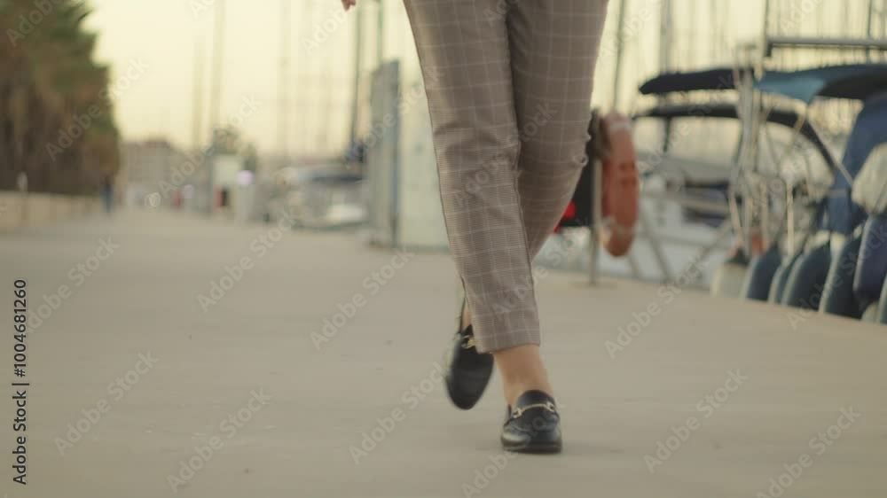 Businesswoman Walk Confidently Through Marina, Wear Stylish Loafers and Dress Pants. Camera Captures Movements Against Backdrop of Boats and Sparkling Sea Businesswoman Walk Confidently Through Marina, Wear Stylish Loafers and Dress Pants. Camera Captures Movements Against Backdrop of Boats and Sparkling Sea