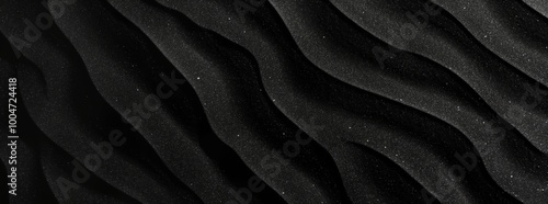 The image is a black and white photo of a beach with a lot of sand and glitter. The sand is spread out in a wavy pattern, and the glitter is scattered throughout the sand