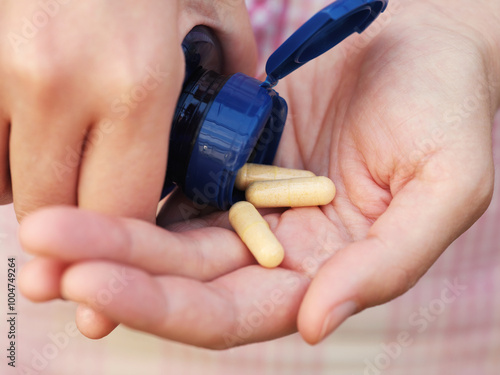 A woman taking Vitamin B Complex capsules out of a bottle. Close up. photo