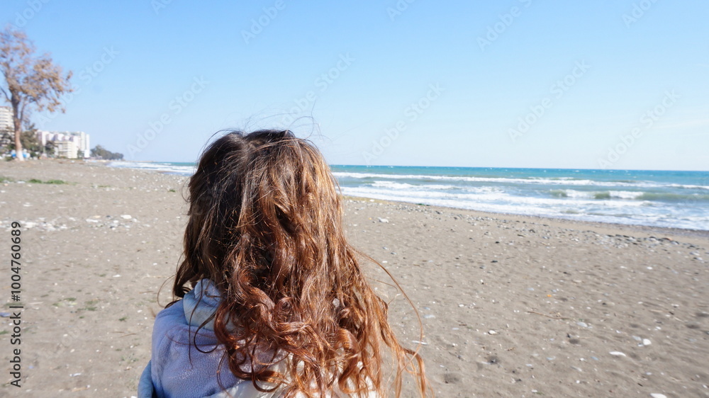 child on the beach in autumn, pure emotions and loose hair. Wind-tangled children's curls on the seashore child on the beach in autumn, pure emotions and loose hair. Wind-tangled children's curls on the seashore