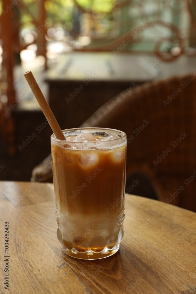 Glass of refreshing iced coffee and straw on wooden table outdoors Glass of refreshing iced coffee and straw on wooden table outdoors