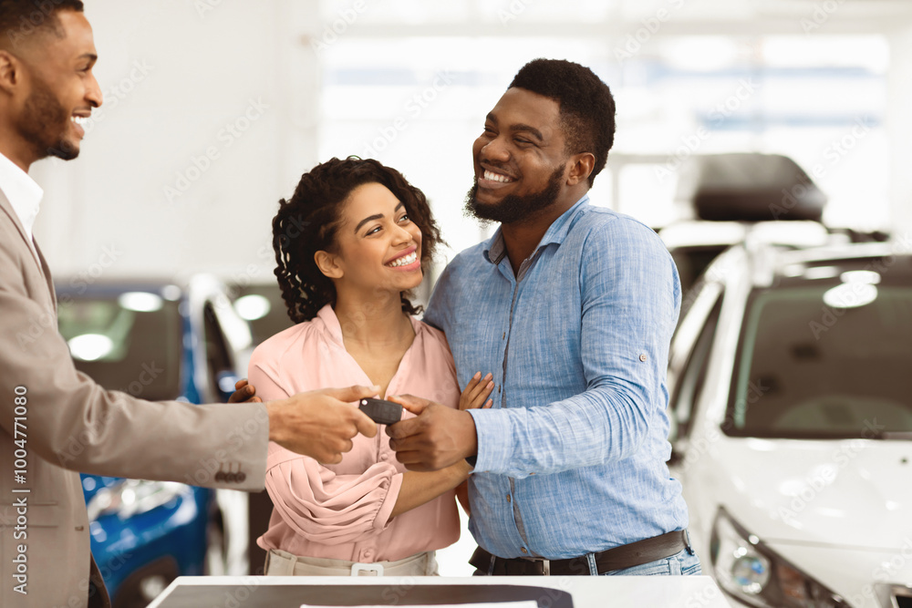 Car Sales. Manager Giving New Auto Key To Family Couple Buying New Vehicle Standing In Dealership Shop. Selective Focus