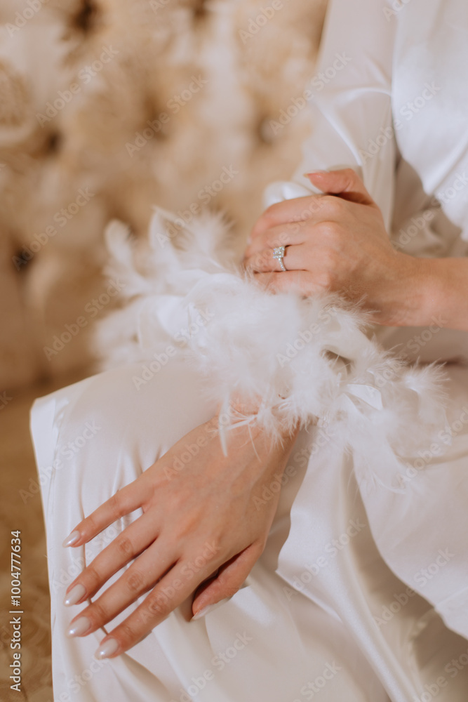 Close-up of hands with engagement ring in white feathered robe. Close-up of hands with engagement ring in white feathered robe.