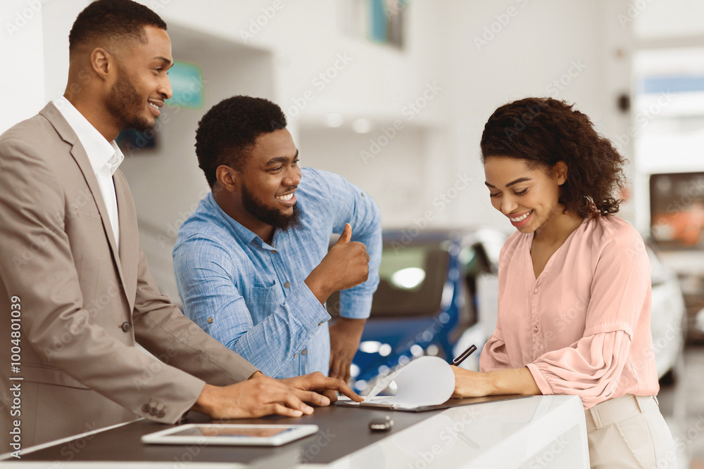 Afro Couple Signing Papers With Car Dealer Buying Auto In Dealership Office. Selective Focus, Panorama Afro Couple Signing Papers With Car Dealer Buying Auto In Dealership Office. Selective Focus, Panorama