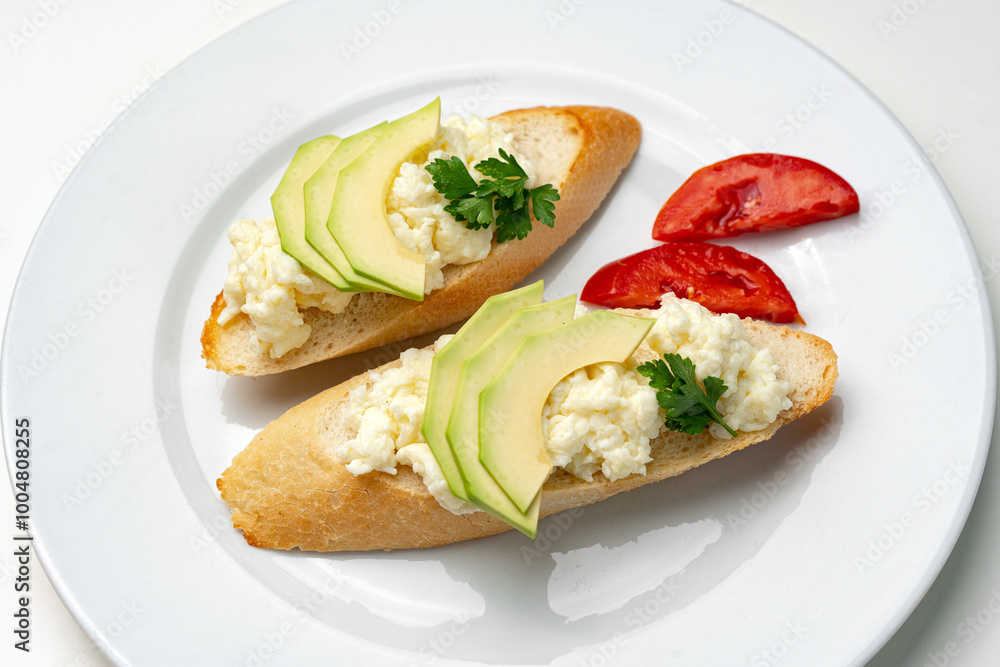 Fresh avocado and cheese spread on toasted bread garnished with cilantro and tomato Fresh avocado and cheese spread on toasted bread garnished with cilantro and tomato