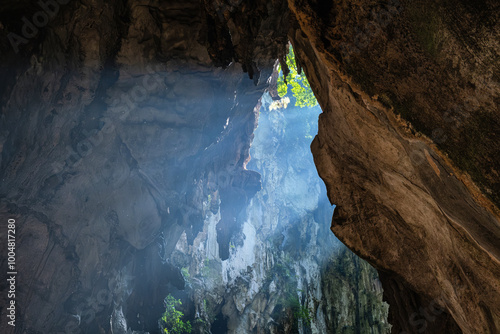 Photography Sunlight piercing through Batu cave entrance, illuminating the rugged rock formations and casting a mystical glow, creating a serene and mysterious atmosphere, Kuala Lumpur, Malaysia