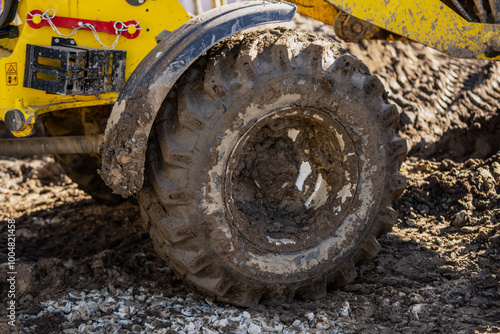 Industrial frontloader wheels and tires close up working in muddy dirty conditions in a construction yard