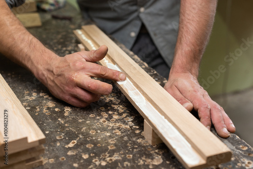 The carpenter smears glue with his finger on an oak part