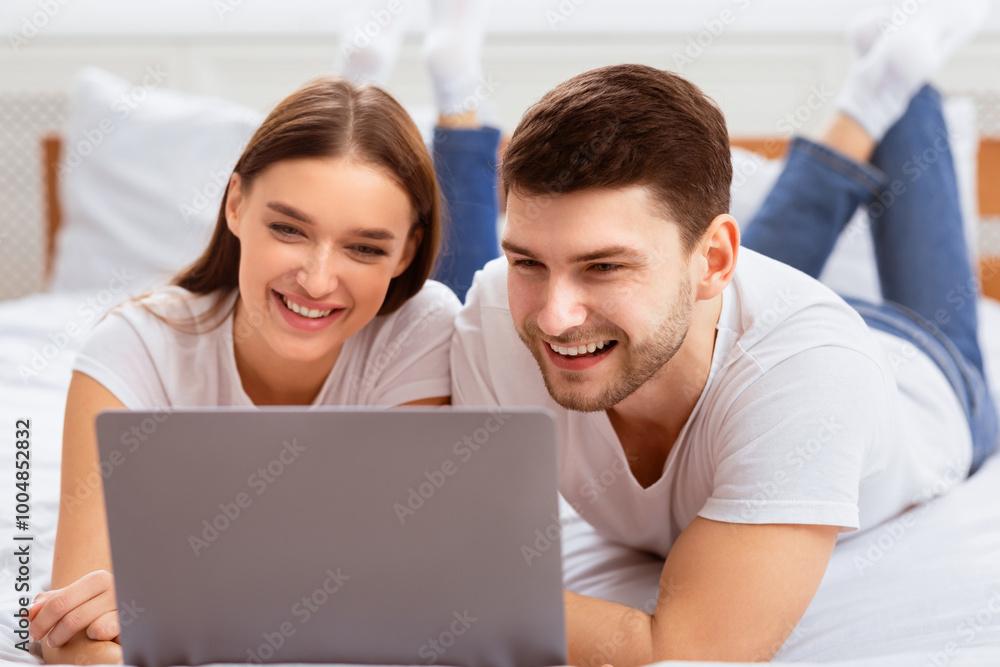 Weekend. Millennial Couple Using Laptop Lying In Bed Watching Movie Spending Weekend At Home. Selective Focus Weekend. Millennial Couple Using Laptop Lying In Bed Watching Movie Spending Weekend At Home. Selective Focus