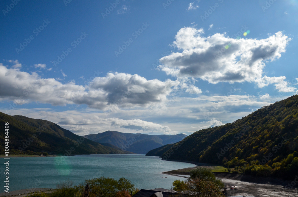 Naklejka premium View from Ananuri Fortress Complex to tranquil vibrant turquoise water surface of Zhinvali Water Reservoir nestled between rolling mountains with the lush greenery of the surrounding terrain. Georgia
