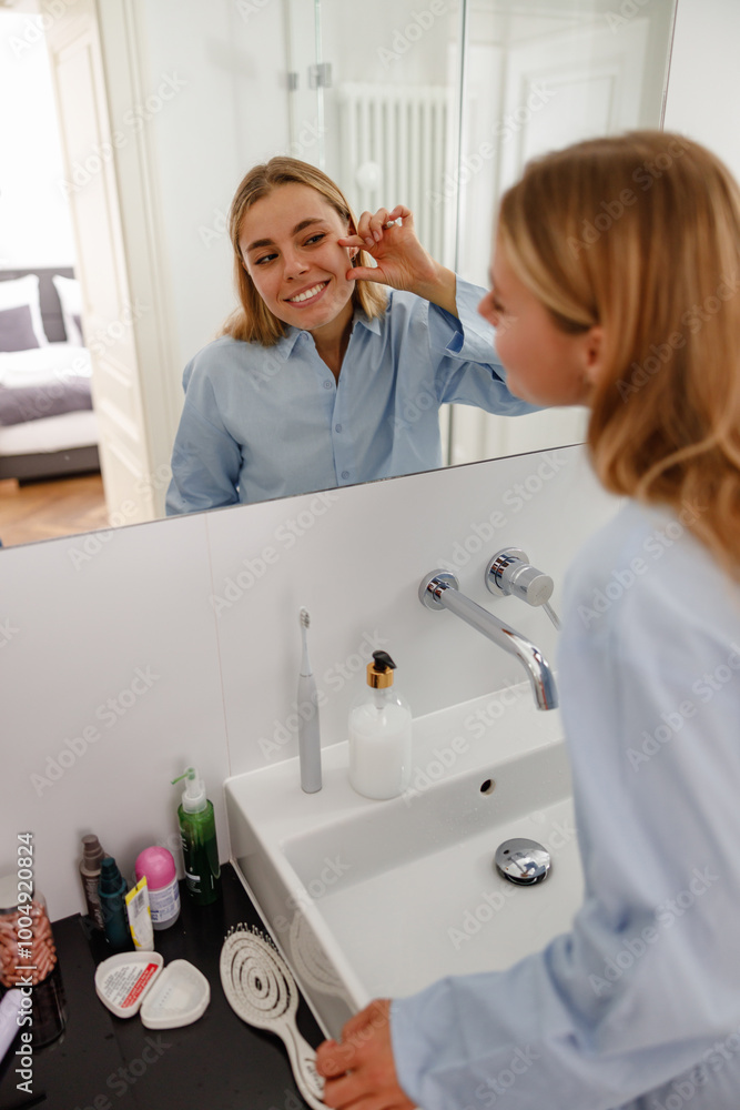 In a bright bathroom, a joyful woman applies skincare products, highlighting her lovely selfcare routine In a bright bathroom, a joyful woman applies skincare products, highlighting her lovely selfcare routine