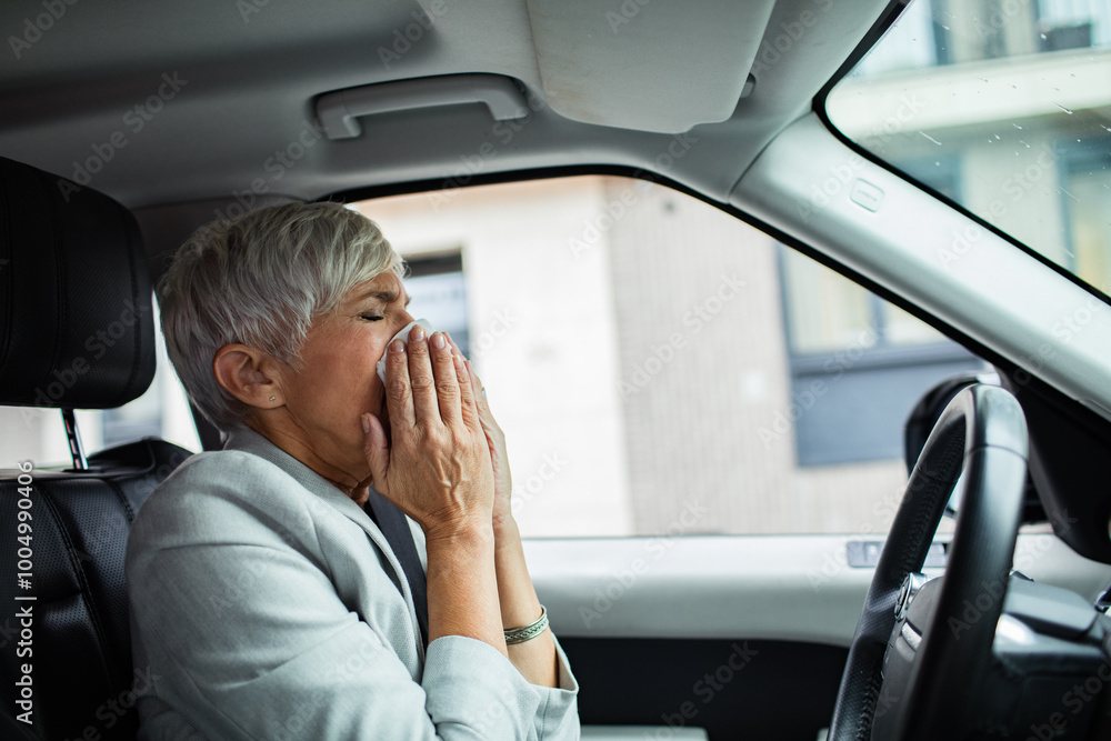 Senior professional woman blowing nose in tissue in car Senior professional woman blowing nose in tissue in car