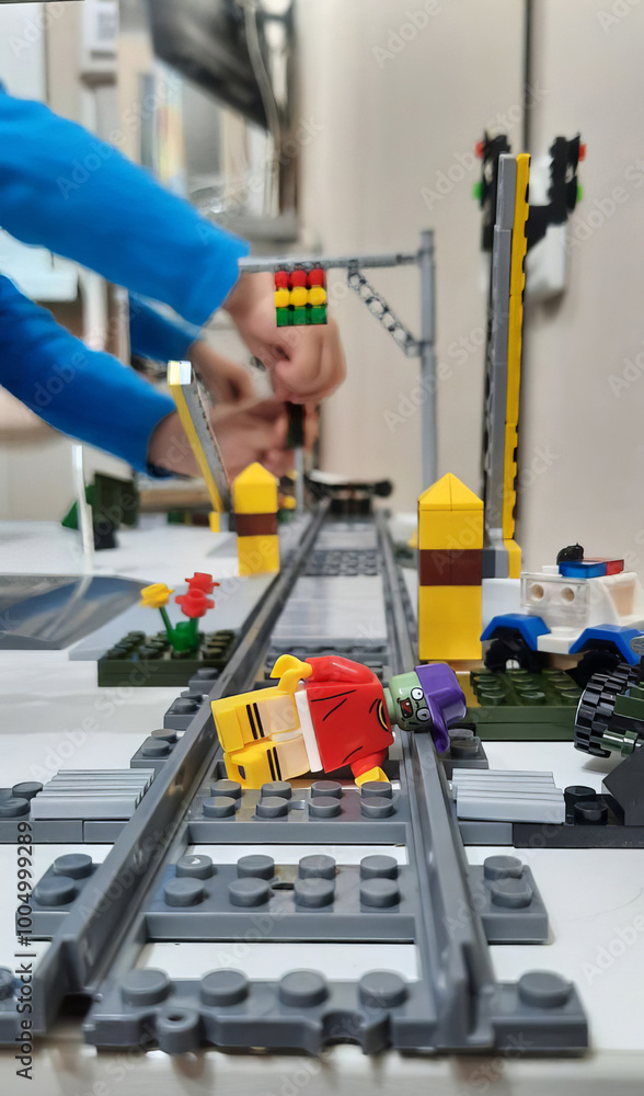 A boy is playing with a railroad and a construction set. toy railway A boy is playing with a railroad and a construction set. toy railway