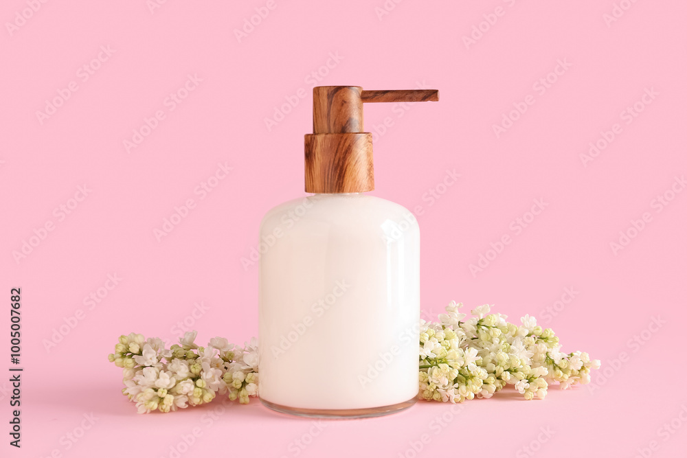 Soap dispenser with white lilac twig on pink background Soap dispenser with white lilac twig on pink background