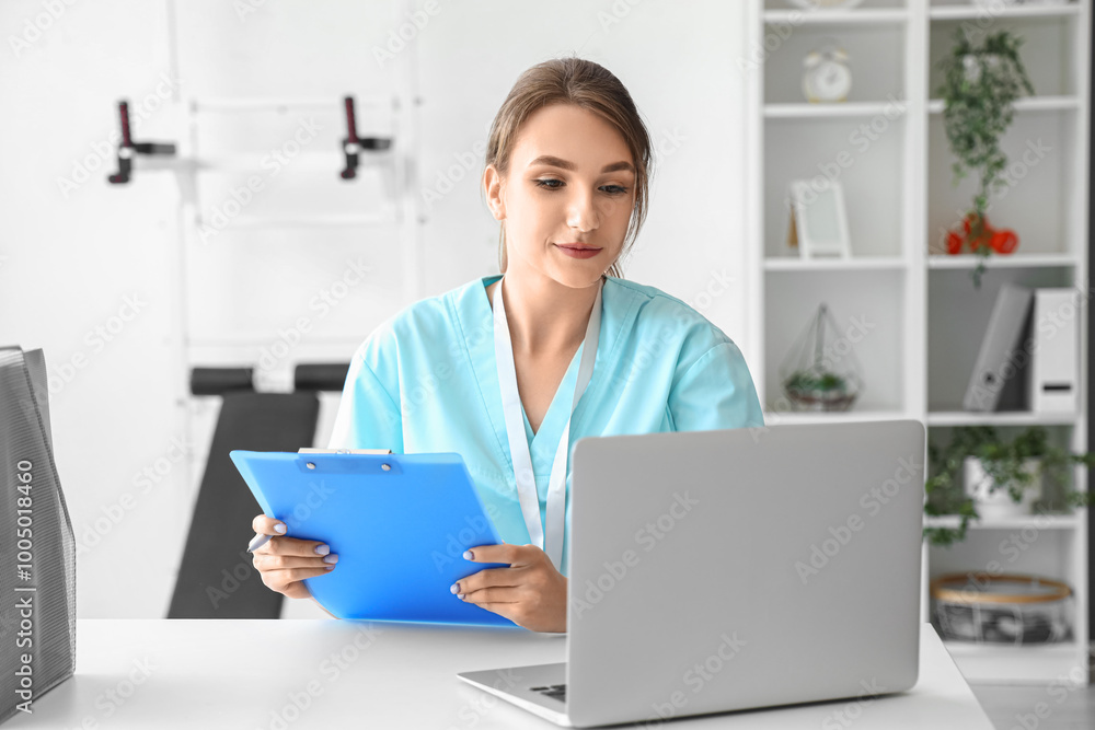 Female medical intern with clipboard using laptop at hospital Female medical intern with clipboard using laptop at hospital