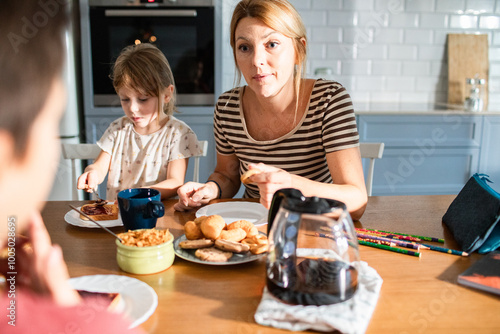 Mother eating breakfast with her kids on kitchen table