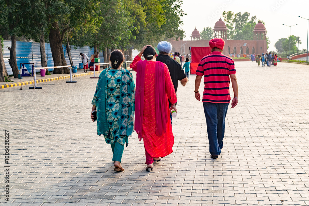 Four people are walking away from the camera on a cobblestone street in india Four people are walking away from the camera on a cobblestone street in india