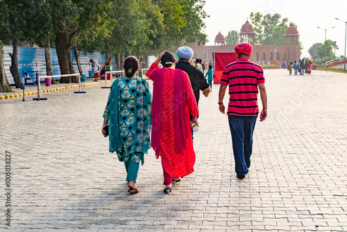 Four people are walking away from the camera on a cobblestone street in india