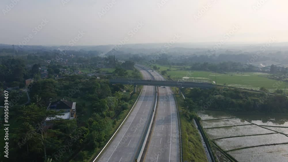 drone video of vehicles passing on the highway under a bridge with villages on the edge during fog in the morning, the drone is in a stationary position and the camera is facing forward
drone video of vehicles passing on the highway under a bridge with villages on the edge during fog in the morning, the drone is in a stationary position and the camera is facing forward