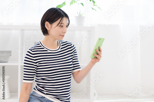 部屋でスマホを見る女性