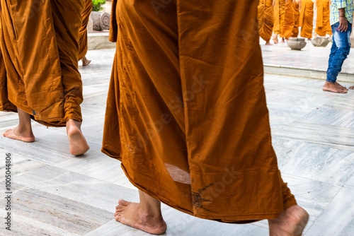 Buddhist monks walking barefoot in traditional saffron robes inside a temple in india