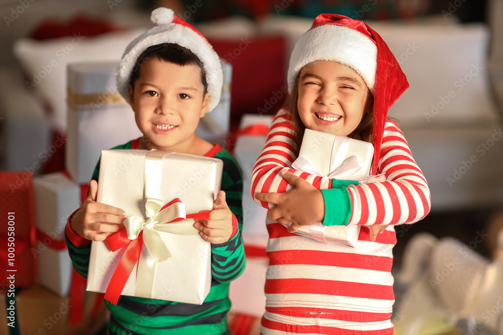 Cute little children in Santa hats with presents at home on Christmas eve Cute little children in Santa hats with presents at home on Christmas eve