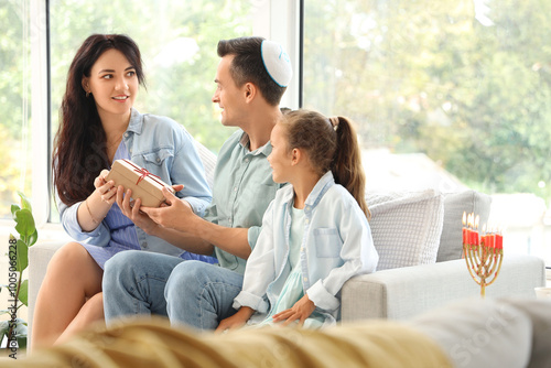 Happy family with gift celebrating Hanukkah at home