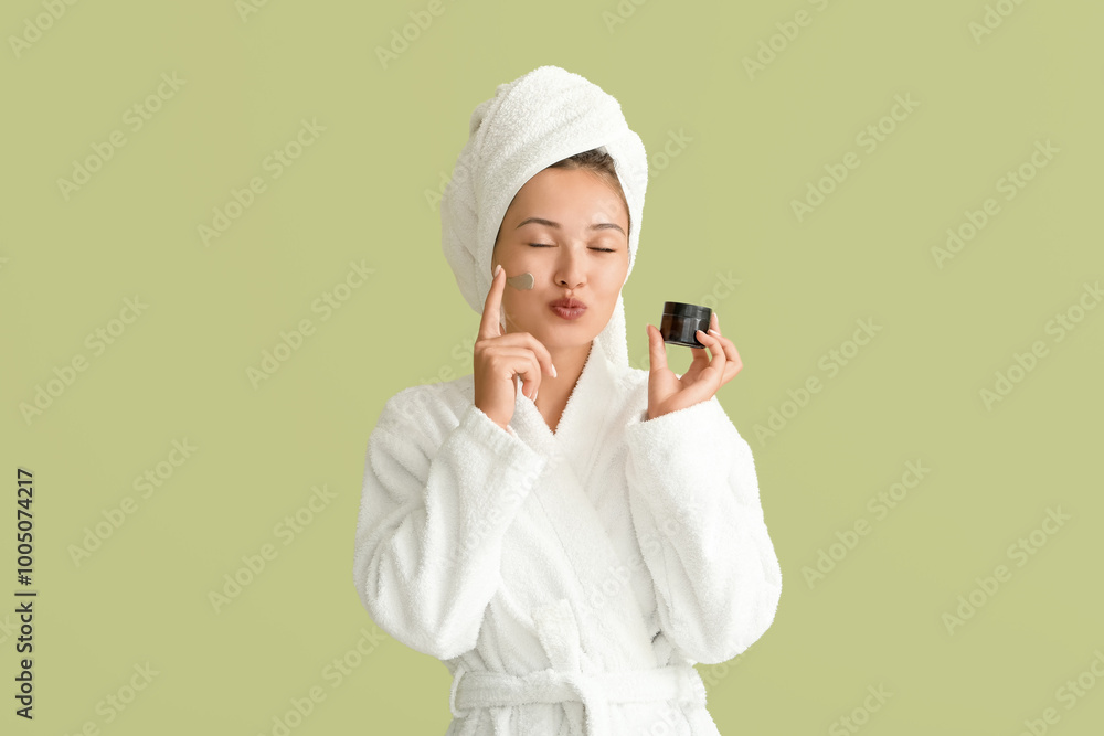 Beautiful Asian woman applying facial mask on green background Beautiful Asian woman applying facial mask on green background