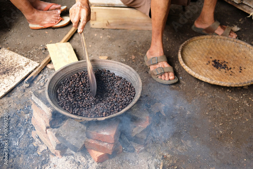 Roasting Coffee on a Charcoal Stove, manually roasted and stirred in an earthen pot. Coffee beans are roasted by hand on a charcoal stove. Purbalingga, Indonesia photo