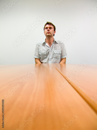 A man in casual clothes in a meeting room in an office/work enviroment.