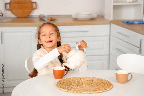 Cute little girl pouring te...