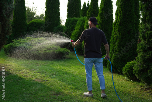 Man watering lawn with hose in backyard