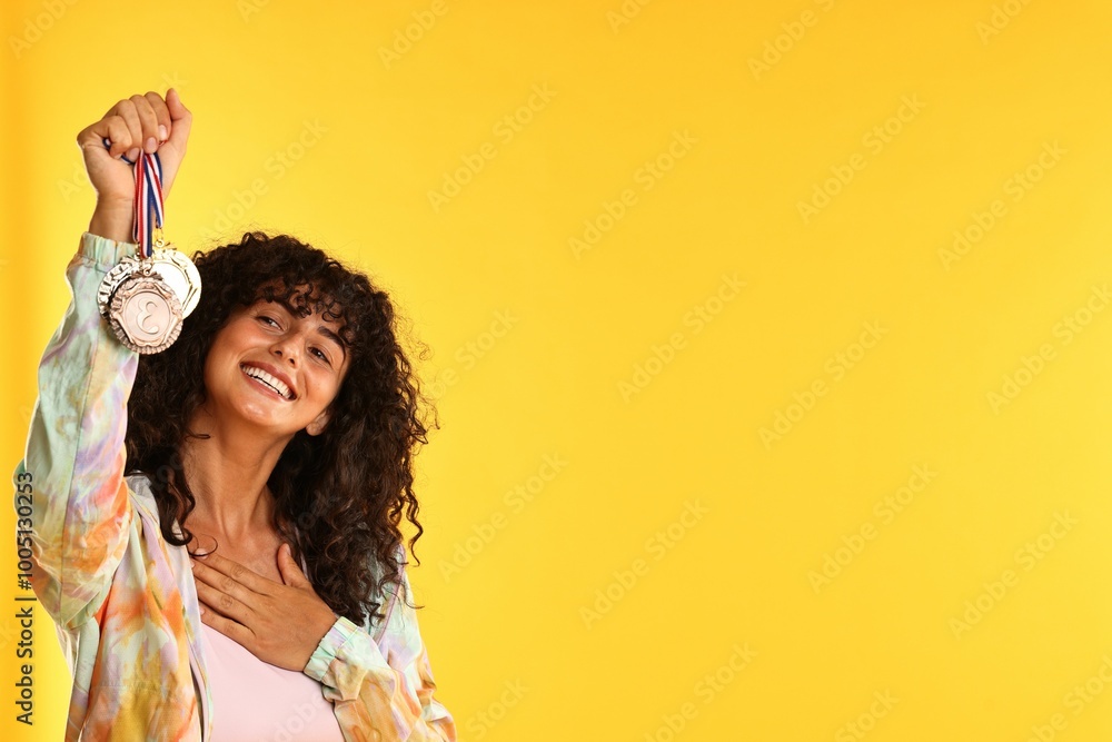 Happy winner showing different medals on yellow background. Space for text Happy winner showing different medals on yellow background. Space for text
