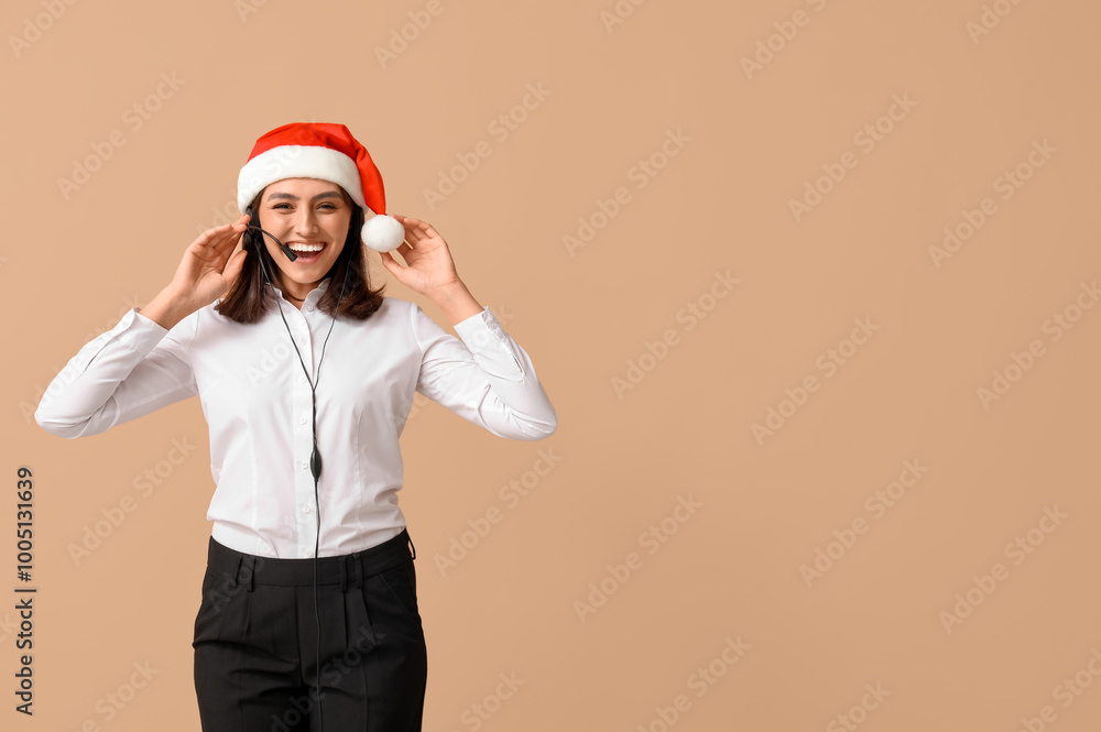 Beautiful female technical support agent in Santa hat on brown background Beautiful female technical support agent in Santa hat on brown background