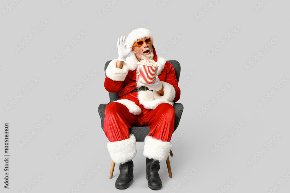 Santa Claus in 3D glasses with bucket of tasty popcorn on grey background Santa Claus in 3D glasses with bucket of tasty popcorn on grey background