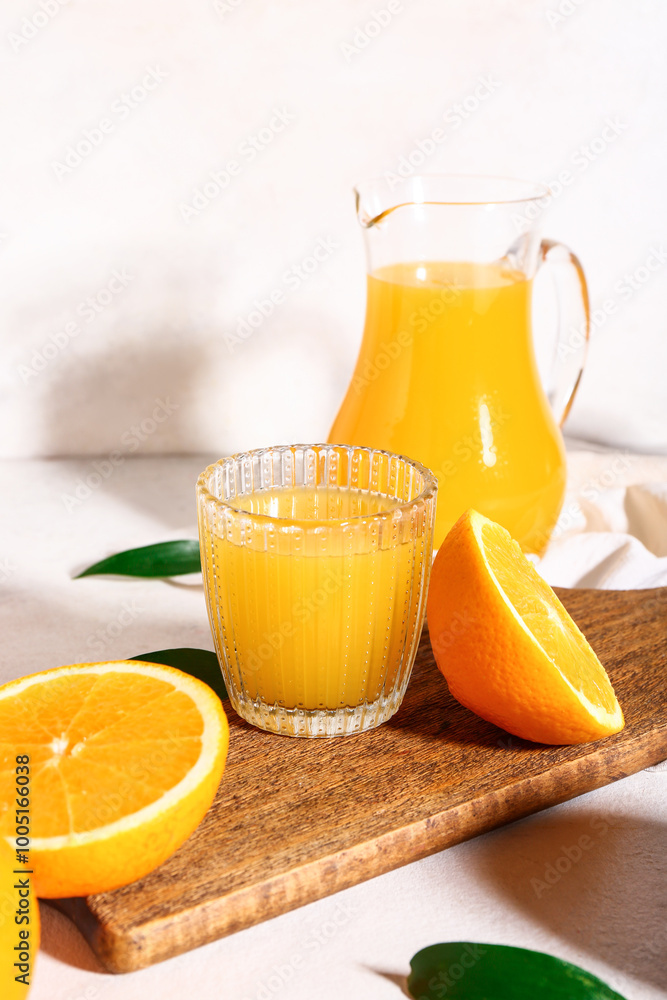 Wooden board with glass and jug of fresh orange juice on white background Wooden board with glass and jug of fresh orange juice on white background