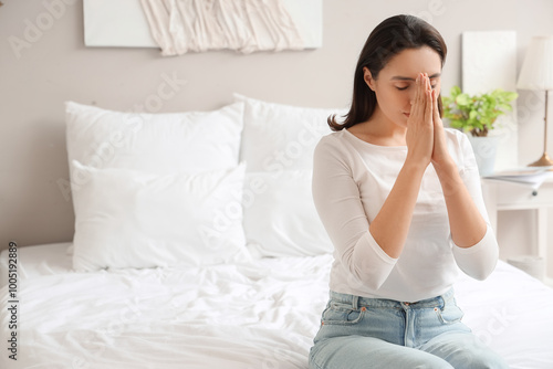 Young woman praying in bedroom
