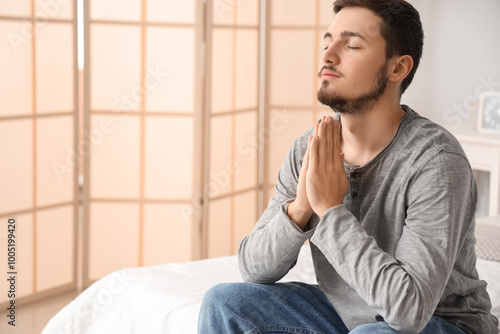 Young man praying in bedroom