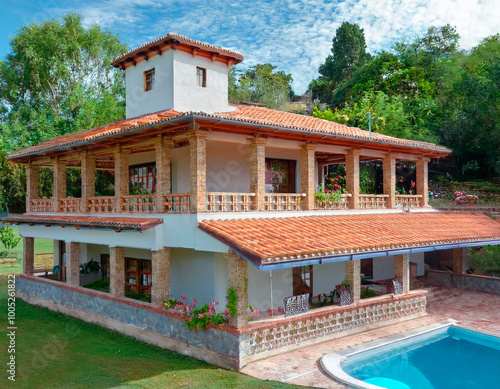 Casa de campo de dos pisos, con teja rojiza y piscina en primer plano. photo