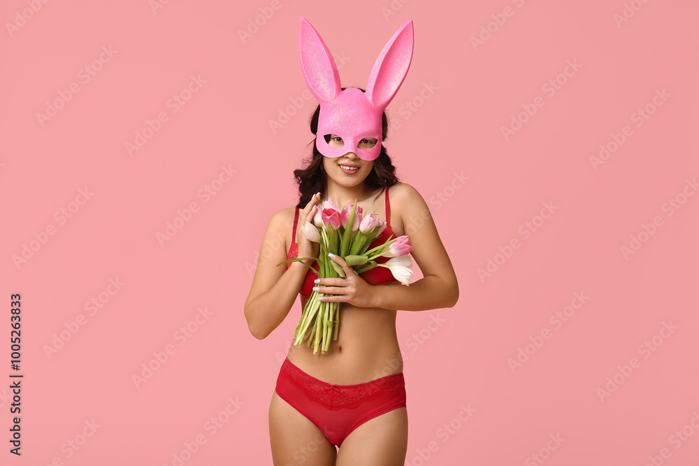 Beautiful young happy Asian woman in bunny mask and sexy lingerie with bouquet of tulips on pink background Beautiful young happy Asian woman in bunny mask and sexy lingerie with bouquet of tulips on pink background