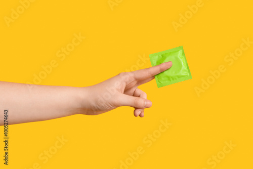 Hand holding green condom p...