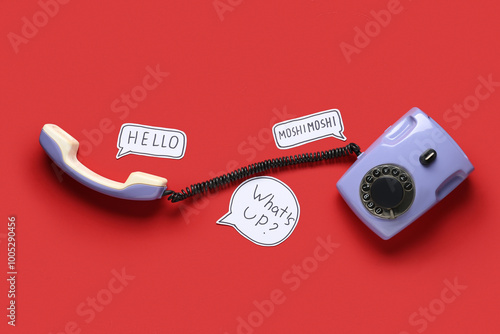 Lilac retro telephone and speech bubbles with text HELLO MOSHIMOSHI WHAT'S UP on red background photo