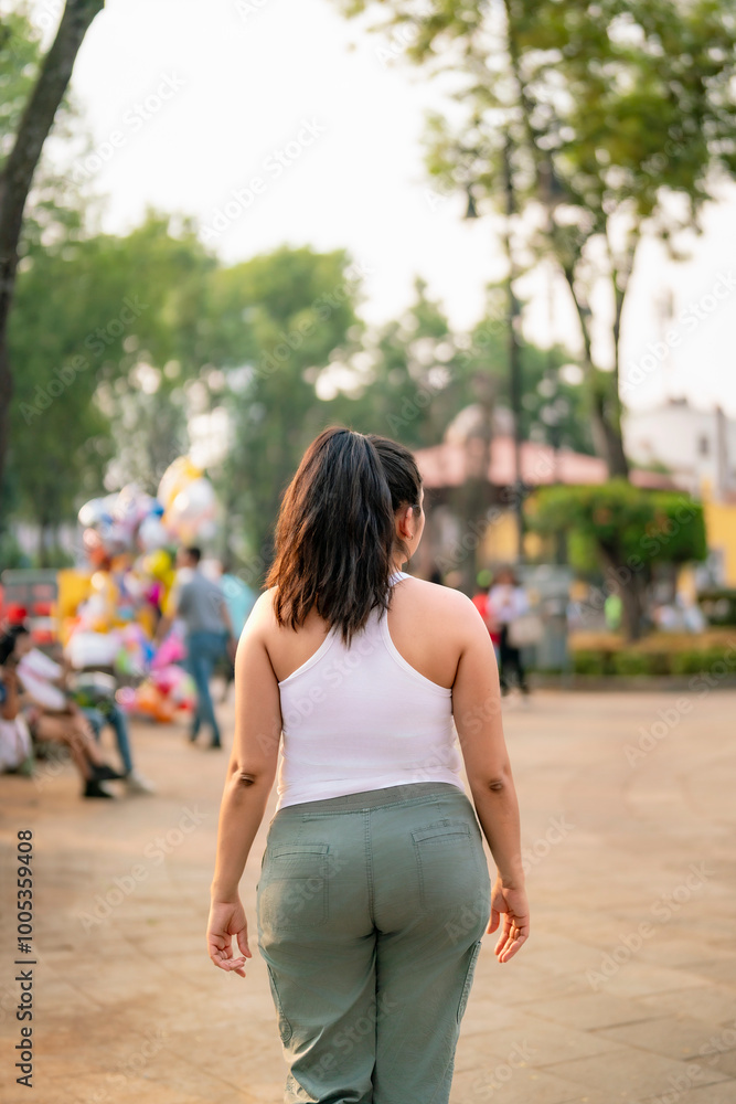 Naklejka premium Unrecognizable young Latina woman smiling and enjoying a sunny day while walking in Coyoacan, Mexico City, Mexico.