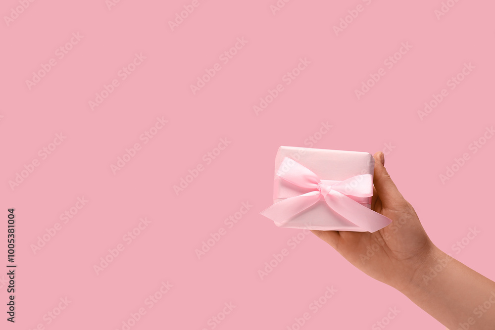 Female hand with gift box on pink background Female hand with gift box on pink background